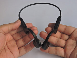 耳をふさがずに音を届ける骨伝導集音器を装着し、快適そうに過ごす高齢の男性のイメージ写真