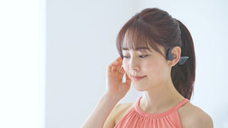骨伝導集音器をこめかみ付近に装着する様子を写した、耳をふさがず音を届ける仕組みのイメージ