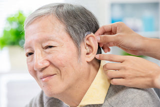 使い慣れた補聴器を手のひらに乗せて見つめる様子、買い替えの時期を考える瞬間を切り取った写真
