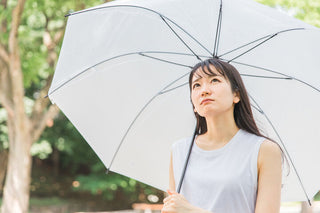 梅雨空の下で傘をさす人物を写した、湿気が招く耳トラブルへの注意を促すイメージ写真