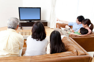 リビングでテレビの音量を気にしながら家族が自然に会話をしている日常の一場面をイメージした写真