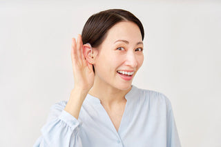 初めて集音器を手に取り、装着しながら聞こえ方を確かめている様子をイメージした写真